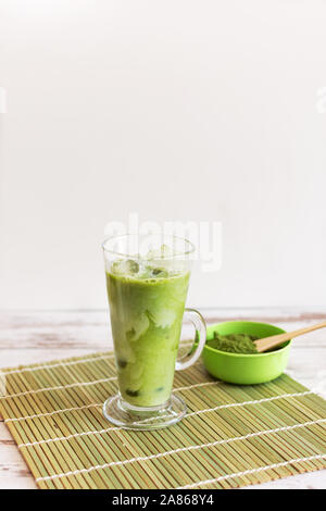 Iced Matcha Latte trinken in Tumbler Glas mit Kokosmilch Gießen von Krug von Hand kopieren. Erfrischende Sommer vegane Getränke kalt trinken. Stockfoto