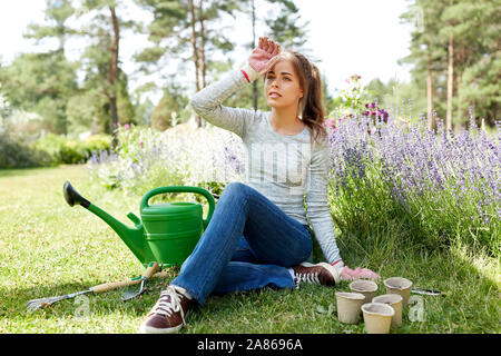 Müde junge Frau mit Garten Werkzeuge im Sommer Stockfoto