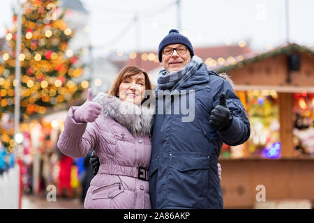 Senior Paar zeigt Daumen bis zum Weihnachtsmarkt Stockfoto