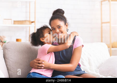 Kleines afrikanisches Mädchen ihre ältere Schwester zu Hause küssen Stockfoto