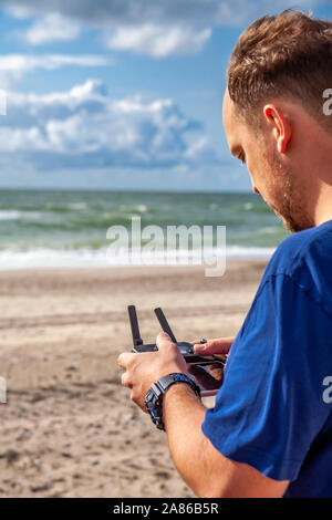 Mann fliegen sein Drone mit Hilfe einer Fernbedienung am Strand. Stockfoto