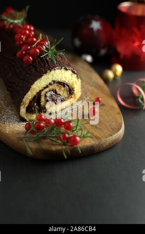 Schokolade Weihnachten Yule Log, Buche de Noel auf Holz Schneidebrett. Weihnachten Dekoration auf dunklem Hintergrund. Nahaufnahme Stockfoto