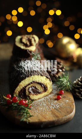 Schokolade Weihnachten Yule Log, Buche de Noel auf Holz Schneidebrett. Weihnachten Dekoration auf dunklem Hintergrund. Nahaufnahme Stockfoto