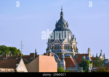 Blick auf die Kuppel der Neuen Synagoge gegen den blauen Himmel, hoch über den Dächern der Stadt Szeged in Ungarn. Stockfoto