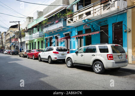 SANTO DOMINGO, DOMINIKANISCHE REPUBLIK - 26. JUNI 2019: Autos am Straßenrand entlang der bunten Häuser der kolonialen Teil der Stadt geparkt Stockfoto