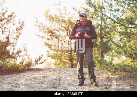 Männliche Fotograf mit der Kamera Arbeiten in der Natur in Wald. Ältere männliche Tourist, Foto der wilden Natur. Stockfoto
