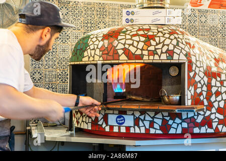 Milton Keynes, Dezember 21,2018. Koch setzt Gourmet frisch zubereitete Pizza auf dem Steinofen Stockfoto