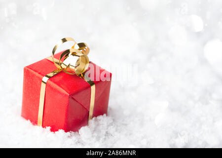 Roter Geschenkbox mit goldenen Bogen in die schneeverwehung. Weihnachten und Neujahr Grußkarte mit Platz für Text.
