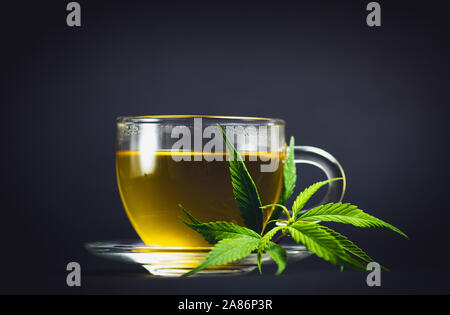 Marihuana Kräutertee in ein Glas und Cannabis Blätter Stockfoto