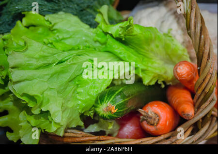 Frisches Gemüse im Korb auf grünem Hintergrund. Stockfoto