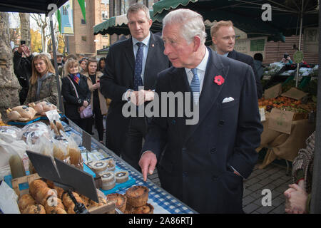 Prinz Charles läuft durch Meet and Greet, seine Sicherheitsbeamten stehen hinter ihm. Swiss Cottage Farmers Market, wir treffen Stände. Es ist der 20. Jahrestag des London Farmers Market. Prinz Charles und die Herzogin von Cornwall besuchten ihn. 2019 zum Gedenken an die Veranstaltung. 2010er Jahre HOMER SYKES Stockfoto