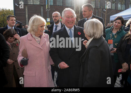 Prinz Charles und Camilla die Herzogin von Cornwall auf dem Schweizer Bauernmarkt, wo sie Stände treffen. Charles entspannte und lachende, glückliche Camilla mit einem Kuchenschneider. Ihre drei Leibwächter stehen hinter ihnen. Es ist der 20. Jahrestag des London Farmers Market. UK 2019. 2010er Jahre HOMER SYKES Stockfoto