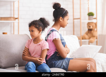 Grumpy afrikanischen amerikanischen Schwestern zurück sitzen auf der Couch zu zurück Stockfoto