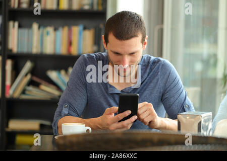 Vorderansicht Portrait von ein ernster Mann Kontrolle Telefon Inhalt in einer Bar oder Home Stockfoto