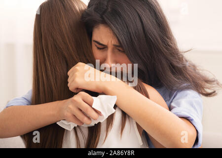 Frau umarmt depressiven Freund sitzt auf einem Sofa Indoor, selektiven Fokus Stockfoto