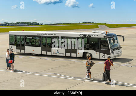 BRISTOL, England - AUGUST 2019: Menschen zu Fuß über das Vorfeld nach Ankunft am Flughafen Bristol. Im Hintergrund ist ein Transfer vom Flughafen Bus. Stockfoto