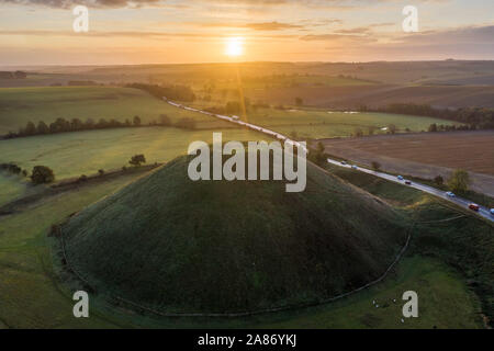 Silbury Hill, Nr Avebury, Wiltshire, UK. 4. November 2019. Drone Bild der Sonnenaufgang über der Jungsteinzeit Damm der Silbury Hill in Wiltshire. Stockfoto