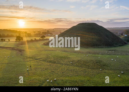 Silbury Hill, Nr Avebury, Wiltshire, UK. 4. November 2019. Drone Bild der Sonnenaufgang über der Jungsteinzeit Damm der Silbury Hill in Wiltshire. Stockfoto