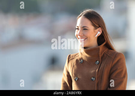 Glückliches Mädchen mit drahtlosen Kopfhörer anf braun jacke Musik im Winter Stockfoto