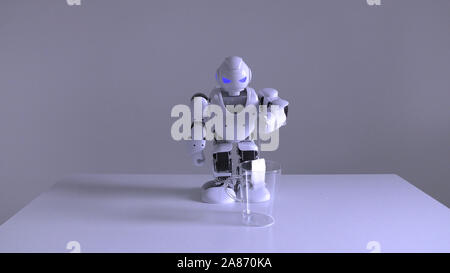 Eine inländische Android humanoide Roboter üben Teezubereitung für seinen Meister durch Einweichen einen Teebeutel in ein leeres Glas Wasser Stockfoto