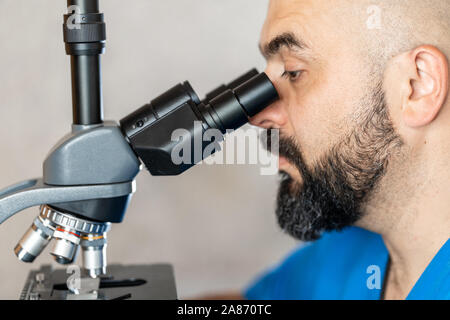 Männliche Laboratory Assistant Prüfung biomaterial Proben in ein Mikroskop Stockfoto
