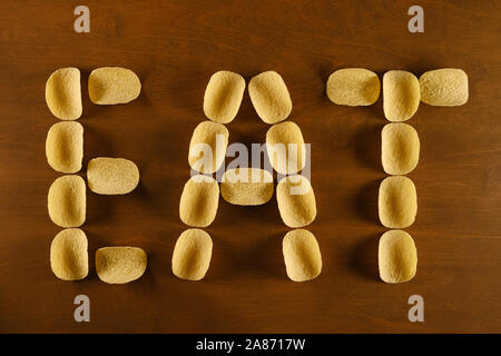 Kartoffel Chips auf einem Holztisch, Hintergrund mit Text "Essen", die Konzeption zum Thema fast food, ungesunde Ernährung und erhöhtes Risiko für Fettleibigkeit Stockfoto