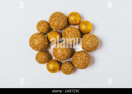 Festliche flach Zusammensetzung gold Glitter Weihnachten Kugeln auf weißem Hintergrund, Ansicht von oben. Stockfoto