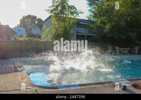 Eine Aktion des Splash durch einen Sprung in einen Pool an einem sommerlichen Tag erstellt. Stockfoto