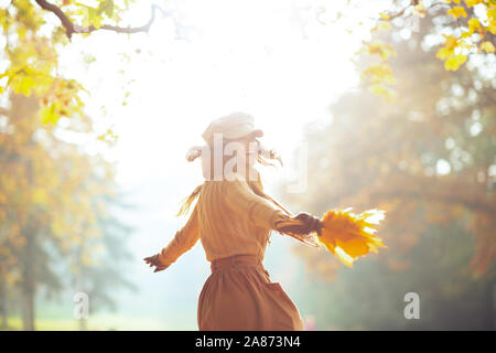 Hallo Herbst. lächelnden jungen Frau in die jacke, rock, hut, handschuhe und Schal mit gelben Blättern Spaß Zeit draussen im Herbst Park. Stockfoto