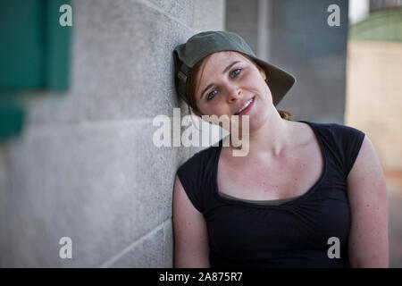 Frau steht neben Betonwand Stockfoto