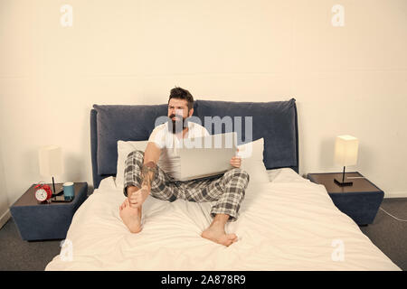 Die späte Stunden. brutale schläfrigen Mann im Schlafzimmer. reife Männer mit Bart im Pyjama auf dem Bett. Schlafen und wach. Energie und Müdigkeit. Geschäftsmann mit Computer. bärtiger Mann hipster Arbeiten am Laptop. Stockfoto