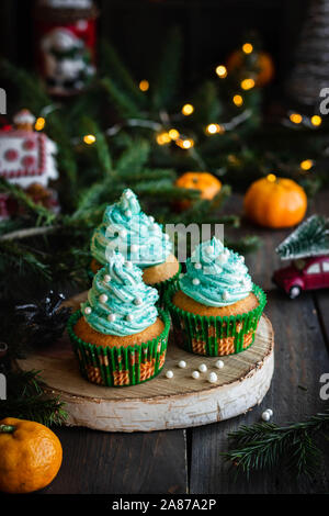 Mandarin Cupcakes mit festlich geschmückten Kappen von Butter Creme. Neues Jahr und Weihnachten Dessert. Stockfoto