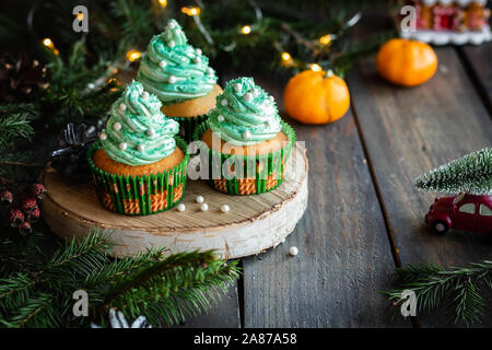 Mandarin Cupcakes mit festlich geschmückten Kappen von Butter Creme. Neues Jahr und Weihnachten Dessert. Stockfoto