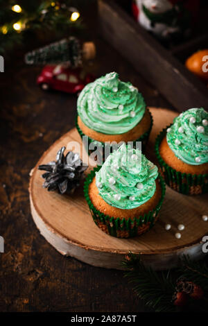 Mandarin Cupcakes mit festlich geschmückten Kappen von Butter Creme. Neues Jahr und Weihnachten Dessert. Stockfoto