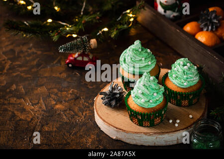 Mandarin Cupcakes mit festlich geschmückten Kappen von Butter Creme. Neues Jahr und Weihnachten Dessert. Stockfoto