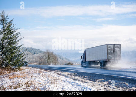 Zwei big Rigs semi Trucks mit unterschiedlichen Sattelaufliegern aufeinander zu gehen nach jeder seine eigene Route im Winter gefährlich nasse Straße heben Clou Stockfoto