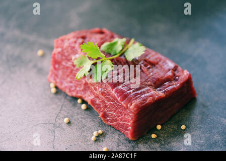 Rohes Fleisch Rindfleisch Steak mit Gewürzen Knoblauch auf Holz Schneidebrett und schwarzem Hintergrund, Ansicht von Oben/Frisches Rindfleisch Stück für Steak oder gegrillt Grill Stockfoto