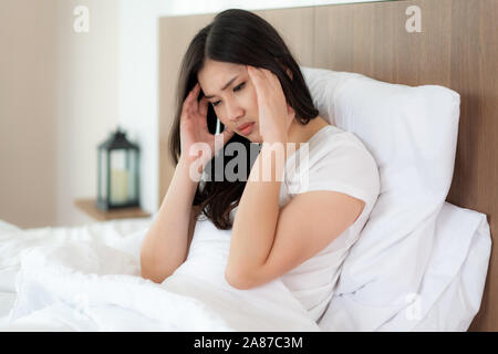 Attraktive junge asiatische Frau Aufwachen auf ihrem Bett ihre Hand von Kopfschmerzen und Suchen unglücklich und Gefühl Kopfschmerzen/Migräne/Stress/krank. Stockfoto