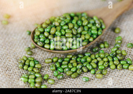 Mung Bohnen in hölzernen Löffel auf dem Sack Hintergrund/Close up Grüne mung bean Saatgut Getreide ganze Körner Stockfoto