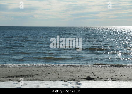 Old Lyme, CT/USA - 3. März 2019: Spuren im Schnee in den Sand führt, dann Meer und Horizont Stockfoto