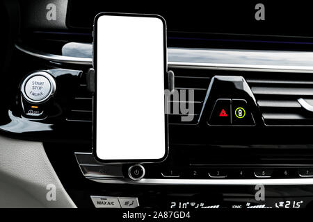 Smartphone in einem Auto für Navigieren oder GPS. Das Fahren eines Autos mit Smartphone im Halter. Mobiltelefon mit isolierten weißen Bildschirm. Leer, leeres Bild.co Stockfoto