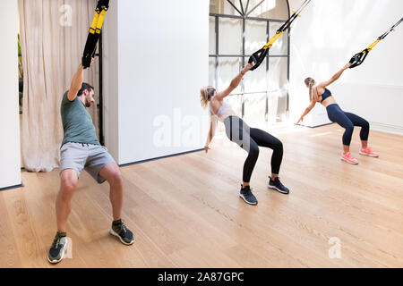Drei Personen, die die Arbeit tun, Trx power zieht in ein Fitnessstudio mit gefederten Bügel und ihre Oberkörper drehen Stockfoto