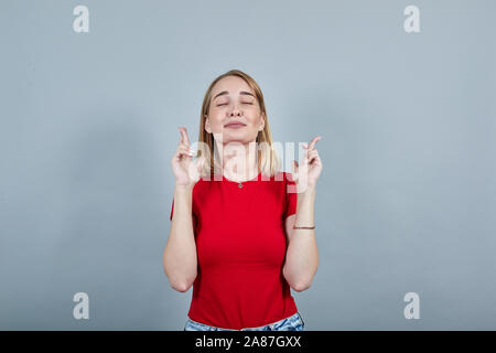 Dame warten auf den besonderen Moment, halten die Finger gekreuzt, die Augen geschlossen und machen möchten Stockfoto