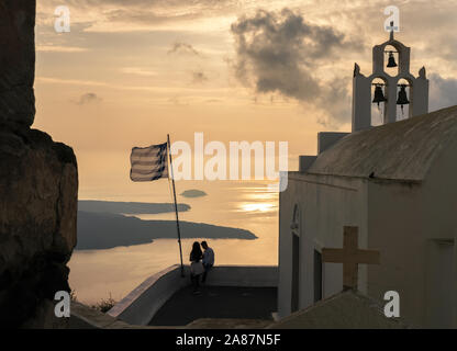 31.Okt 2019 - Santorini, Griechenland. Ein paar einen malerischen Blick auf den Sonnenuntergang über der Ägäis und Fira genießen. Stockfoto