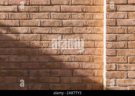 Yellow Brick Wall mit Sonnenlicht und Schatten auf sie, frontale Ansicht, Hintergrund Foto Textur Stockfoto