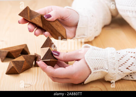 Mädchen sammelt Puzzle sternförmige Dodekaeder. 12-seitige Kleine sternförmige Dodekaeder über einen hölzernen Tisch. Kopieren Sie Platz. Puzzle Konzept. Stockfoto