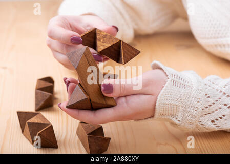 Puzzle details sternförmige Dodekaeder in den Händen eines Mädchens. 12-seitige Kleine sternförmige Dodekaeder über einen hölzernen Tisch. Puzzle Konzept. Stockfoto