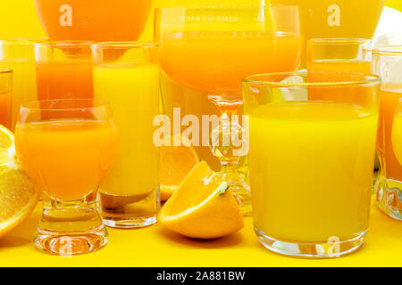 Abstrakte Komposition von Orange und Gelb säfte Getränke in verschiedener Form Gläser mit Orangenscheiben Obst und auf gelben Hintergrund mit kopieren Stockfoto