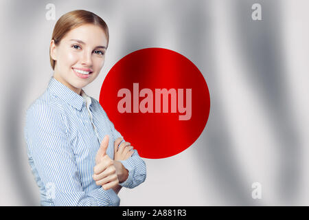 Liebe Japan Konzept. Junge Frau mit Daumen hoch, gegen die japanische Flagge Hintergrund. Reisen, Arbeiten, Ausbildung und Praktikum in Japan Stockfoto