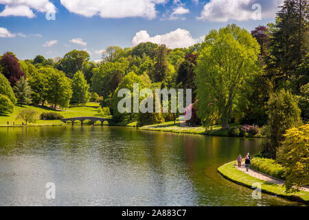 Die Palladianische Brücke und farbenfrohe Rhododendron blüht im Frühjahr an Stourhead Gardens, Wiltshire, England, Großbritannien Stockfoto